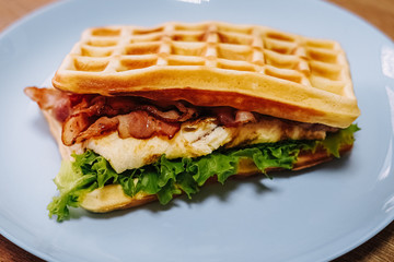 tasty Belgium waffle with lettuce, meat, egg and vegetables served of pretty blue plate