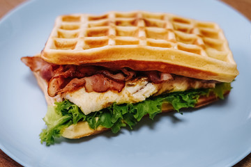 tasty Belgium waffle with lettuce, meat, egg and vegetables served of pretty blue plate