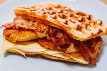 tasty Belgium waffle with lettuce, meat, egg and vegetables served of pretty blue plate