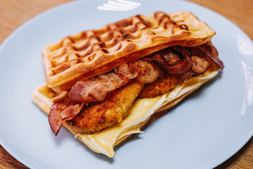 tasty Belgium waffle with lettuce, meat, egg and vegetables served of pretty blue plate
