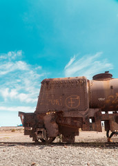 Train Cemetry Bolivia Salt Flats. Bolivian salty desert and blue sky background. Shot in Salar de Uyuni. Rusted, waste, abandoned, locomotive graveyard, railroad concepts. Tourist attraction