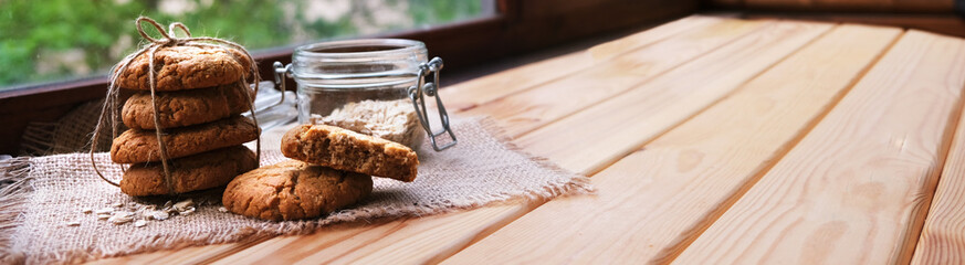 homemade oatmeal cookies tied with a thread on a natural linen napkin with lace. It lies on light wooden background. rustic style. banner with copyspace