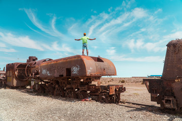 Tourist, Train Cemetry Bolivia Salt Flats. Bolivian salty desert and blue sky background. Shot in Salar de Uyuni. Rusted, waste, abandoned, locomotive graveyard, railroad concepts. Tourist attraction