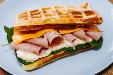 tasty Belgium waffle with lettuce, meat, egg and vegetables served of pretty blue plate