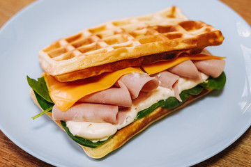 tasty Belgium waffle with lettuce, meat, egg and vegetables served of pretty blue plate