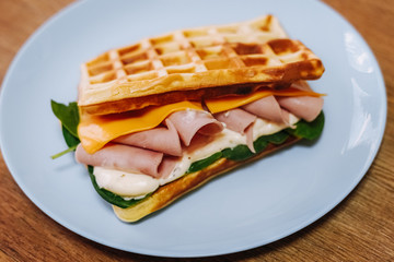 tasty Belgium waffle with lettuce, meat, egg and vegetables served of pretty blue plate