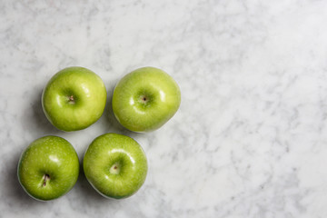 Four granny smith apples on marble background