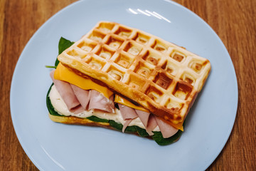 tasty Belgium waffle with lettuce, meat, egg and vegetables served of pretty blue plate