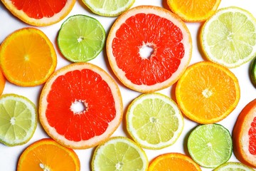 Assorted fresh juicy slices of citrus fruits: grapefruit, orange, lemon and lime. White surface, top view, flat lay.