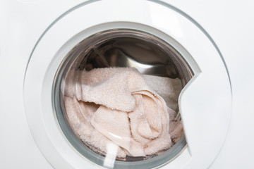 Laundry washing clothes in machine drum front view.