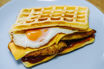 tasty Belgium waffle with lettuce, meat, egg and vegetables served of pretty blue plate