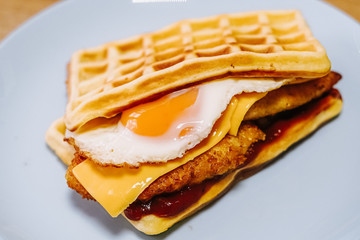 tasty Belgium waffle with lettuce, meat, egg and vegetables served of pretty blue plate