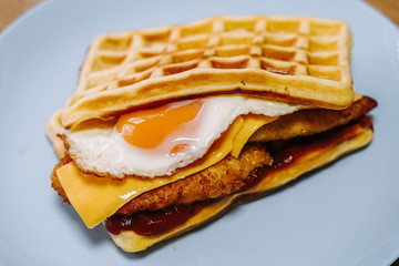 tasty Belgium waffle with lettuce, meat, egg and vegetables served of pretty blue plate