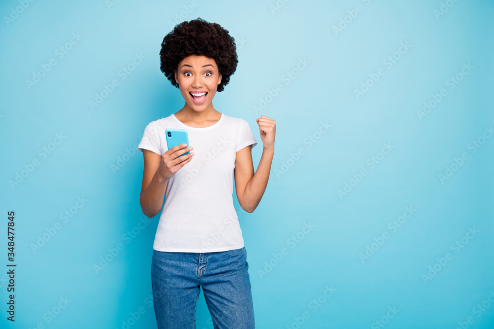 Canvas Prints Photo of crazy beautiful dark skin wavy lady holding telephone hands astonished with many new followers subscribers wear casual white t-shirt jeans isolated blue color background