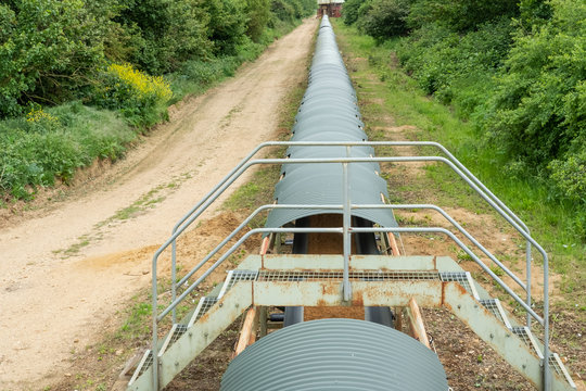 Industrial Quarrying And Aggregate Conveyor System Seen Carrying Fresh Minerals From A Distant Mine. The System Is Covered To Help Prevent Keep The Minerals Dry.