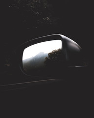 Moody Dramatic Car Window shot showing mountains and trees with dark black background during drive...