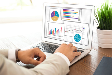 Value concept. Man working with laptop at table indoors, closeup