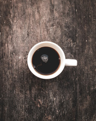 Cup of Black Coffee in White cup from above on wooden table
