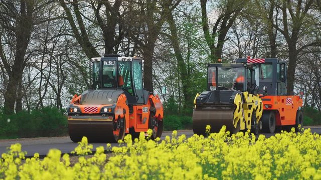 Roller machines make new asphalt roads. The asphalt paver squeezes hot asphalt.