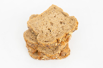 Cereal bread slices for sandwiches laying in pile. Tasty loaf and pastry with poppyseeds and cereals isolated on white background. Studio shot. Top view. Homemade food and baking at home concept