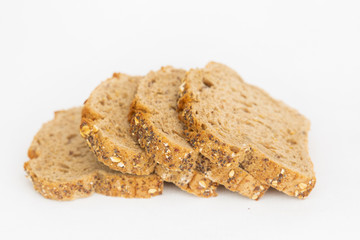 Sliced pieces of cereal bread laying together. Fresh loaf cut for sandwiches isolated on white background. Studio shot. Selective focus. Side view. Homemade food and baking at home concept