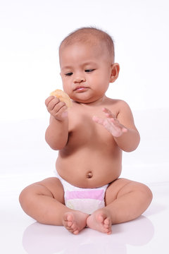 Cute Asian Baby girl wearing diaper holding biscuit