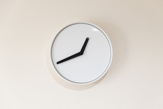 close up view of white minimalist clock without numbers hanging on the wall