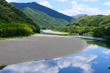 雲を映して流れる、初夏の四万十川。高知、日本。6月上旬。