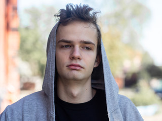 portrait of handsome sad teenager guy in a hood