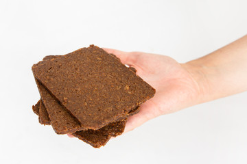Crispbreads laying in pile on palm. Fresh crisps with cereals, oats and seeds isolated on white background. Studio shot. Side view. Home culinary and baking concept