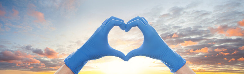 Heart against sky clouds background. Heart builded from hands in doctor gloves