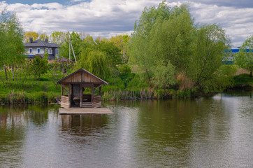 Beautiful quiet lake with a wooden gazebo in a rural cottage village. Country holiday.
