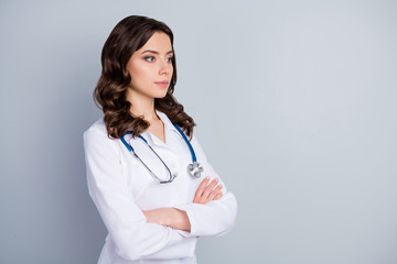 Profile photo of attractive family doc lady patients consultation not smiling virology clinic arms crossed look empty space wear lab coat stethoscope isolated grey color background