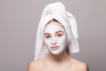 Beauty portrait of woman in towel on head with white nourishing mask or creme on face, white...