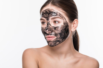 Beautiful woman with a clay or a mud mask on her face isolated over white background