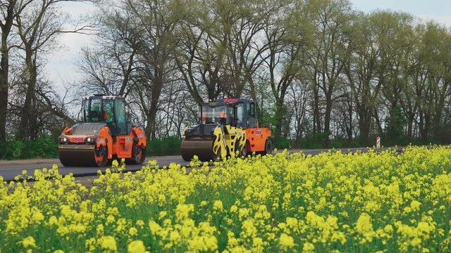 Roller machines make new asphalt roads. The asphalt paver squeezes hot asphalt.