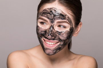 Young beautiful woman in a mask for the face of the therapeutic black mud. Spa treatment