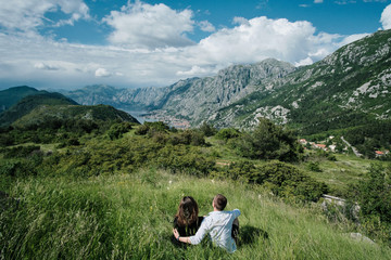 Back view of Romantic couple enjoy the view of the mountains on a sunny day in Montenegro
