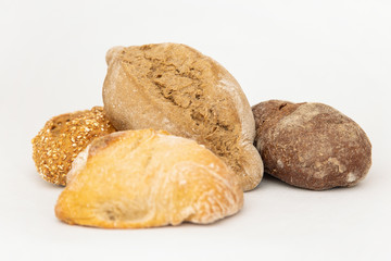 Assortment of different baked breads. Crusty loafs made of wheat and rye flour isolated on white background. Studio shot. Side view. Homemade food and baking at home concept