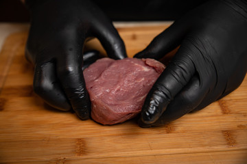 Chef marinates meat steak on a wooden board
