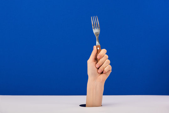 Cropped View Of Woman Holding Stainless Fork Isolated On Blue