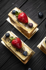French desserts with berries on a dark wooden background