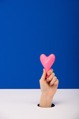 cropped view of woman holding pink heart-shaped balloon isolated on blue