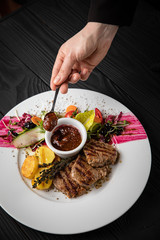 Grilled fillet with vegetables and sauce on a dark background