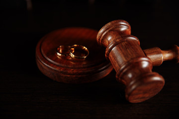 Wedding rings on the stand from a tree, hammer of a judge on a wooden background. Divorce divorce proceedings.