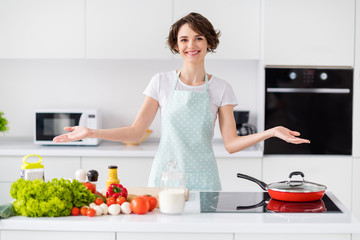 Photo of beautiful attractive housewife weekend saturday morning cooking tasty dinner culinary tv show programme episode good mood wear apron t-shirt stand modern kitchen indoors