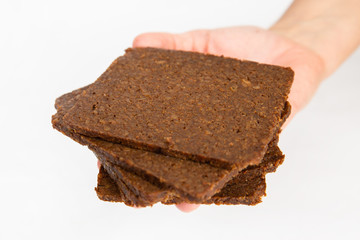 Pile of crunchy crispbreads laying on palm. Fresh crisps with cereals, oats and seeds isolated on white background. Studio shot. Side view. Homemade bakery and cooking at home concept