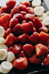 Lot of strawberries and bananas prepared for fondue. Macro shot, vertical poster.