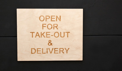 The wooden sign with text: Open for take-out and delivery