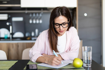 Beautiful young woman writing something in her note pad